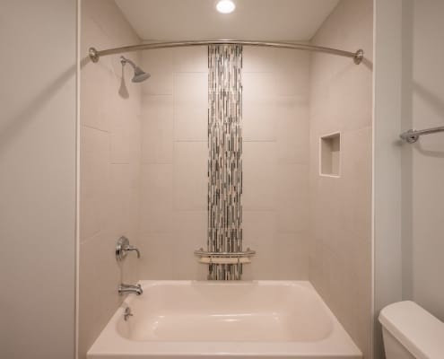 Vertical glass tile feature in shower stall with curved shower curtain bar in fairfax station bath remodel