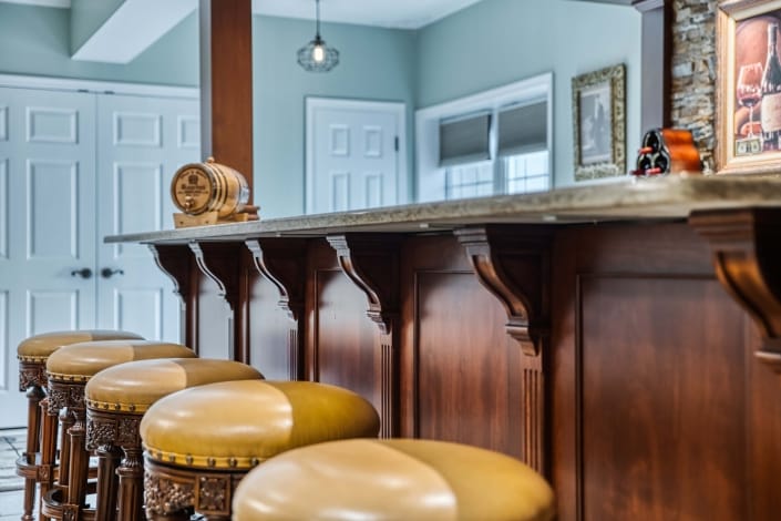 Basement bar English pub designed by Foster Remodeling Solutions with quartz countertop and decorative supports
