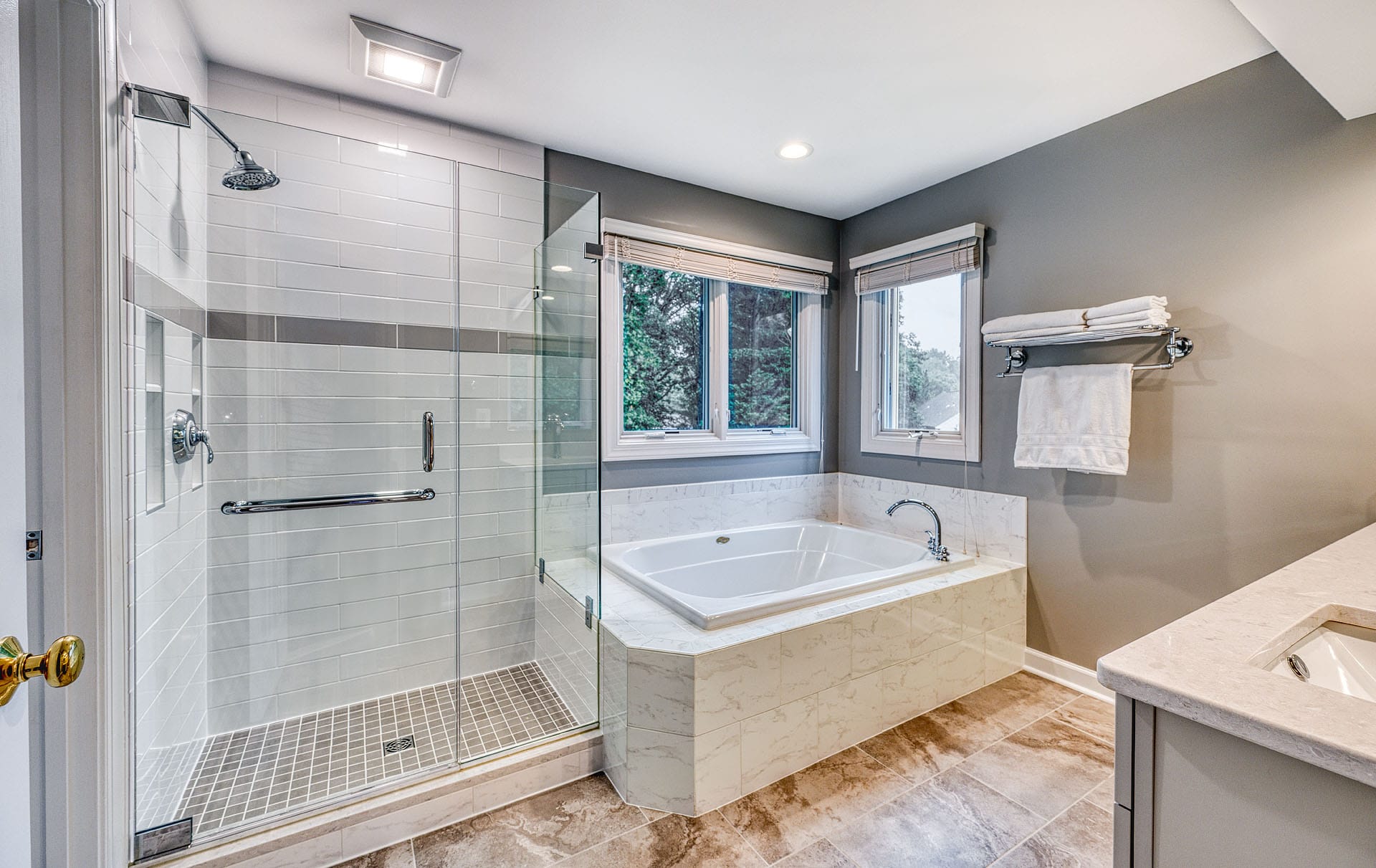 Primary bathroom remodel, Springfield, VA with warm tones including marble tub surround and glass enclosed shower