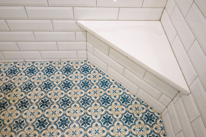 close up photo of bench seat in walk in shower with ornate tile flooring